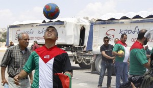 A Palestinian protester holding a Palestinian flag heads a soccer ball next to Israeli border police during a demonstration outside Israel's Ofer military prison